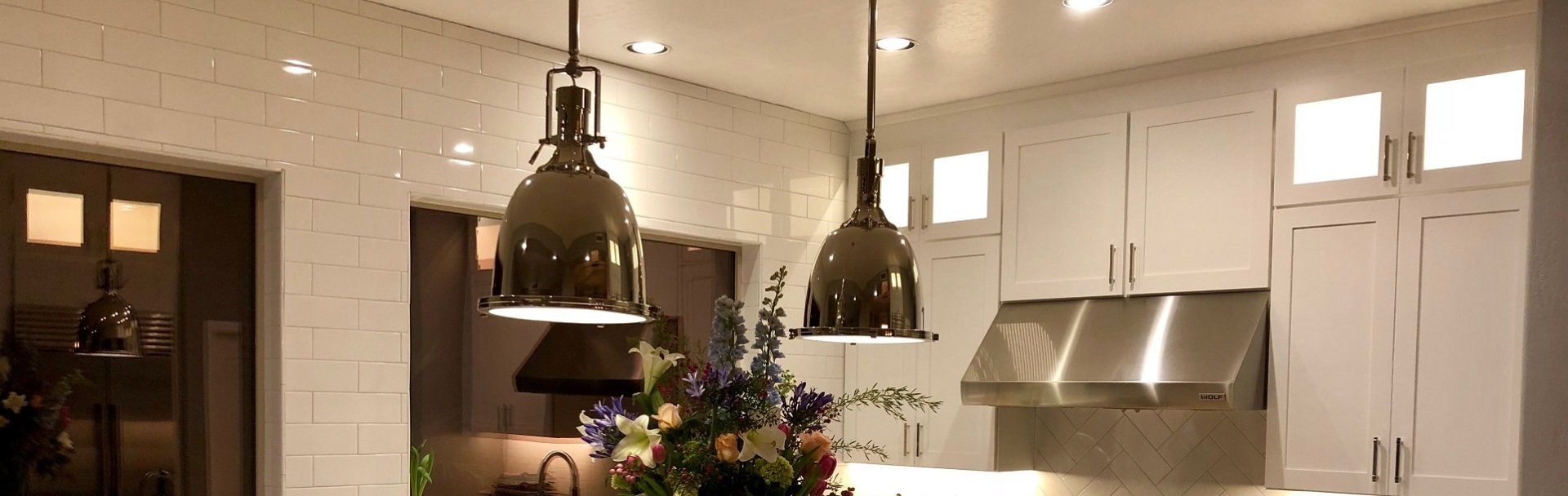 A kitchen with white cabinets and stainless steel appliances and a vase of flowers on the counter.