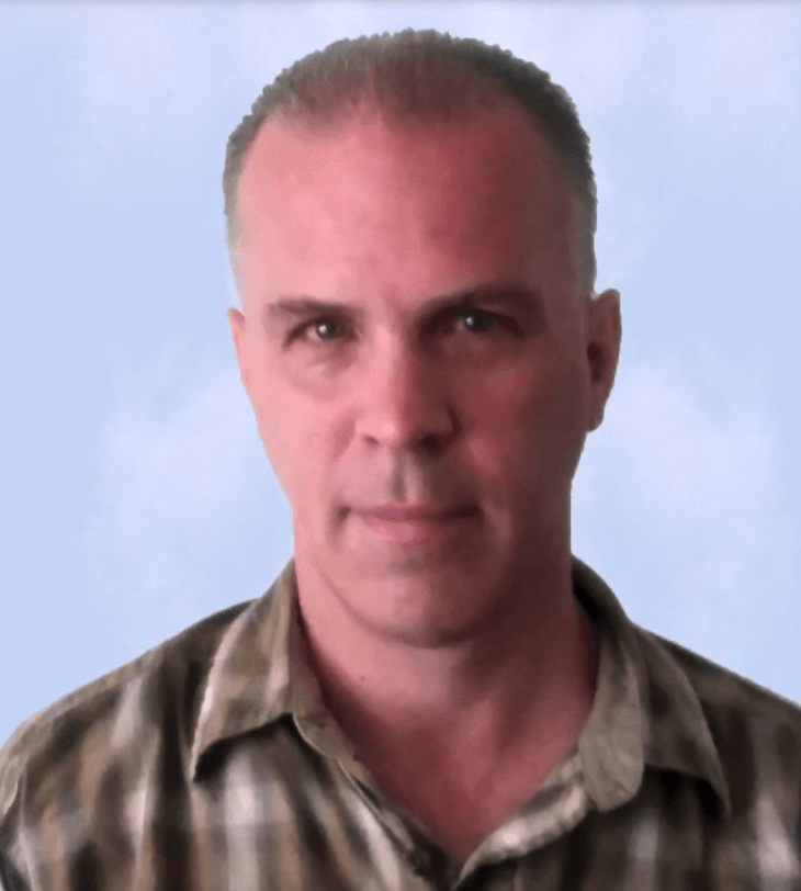A man in a plaid shirt is looking at the camera