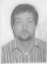A black and white photo of a man with a beard wearing a striped shirt.