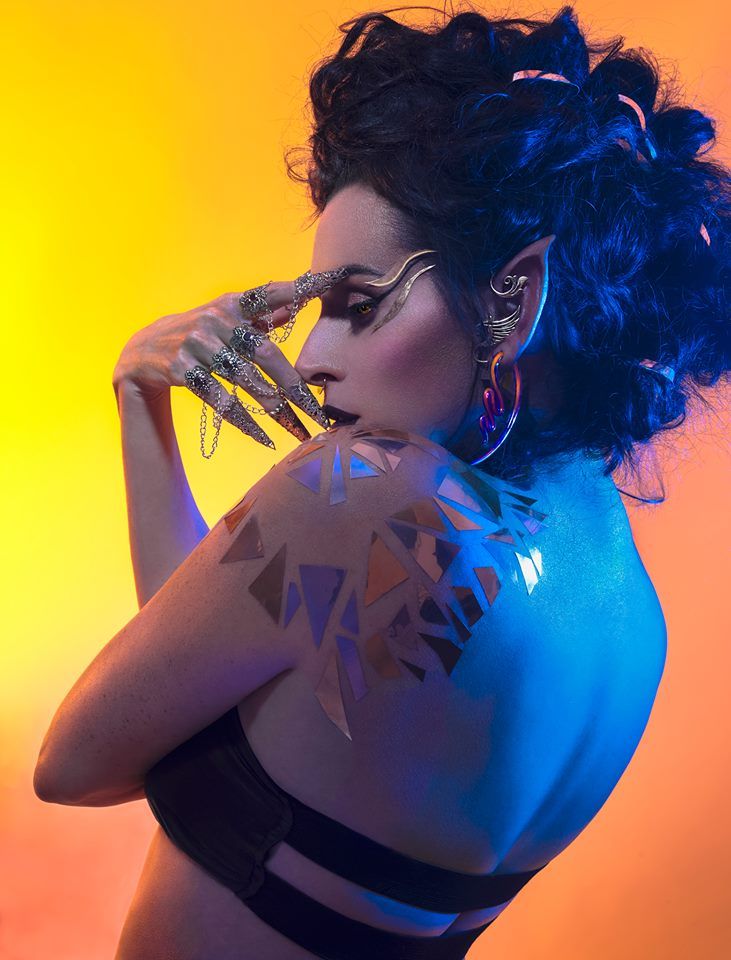 A woman with blue paint on her body and a tattoo on her shoulder.