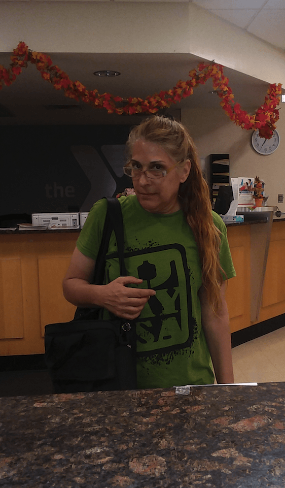 A woman in a green shirt is standing at a counter.