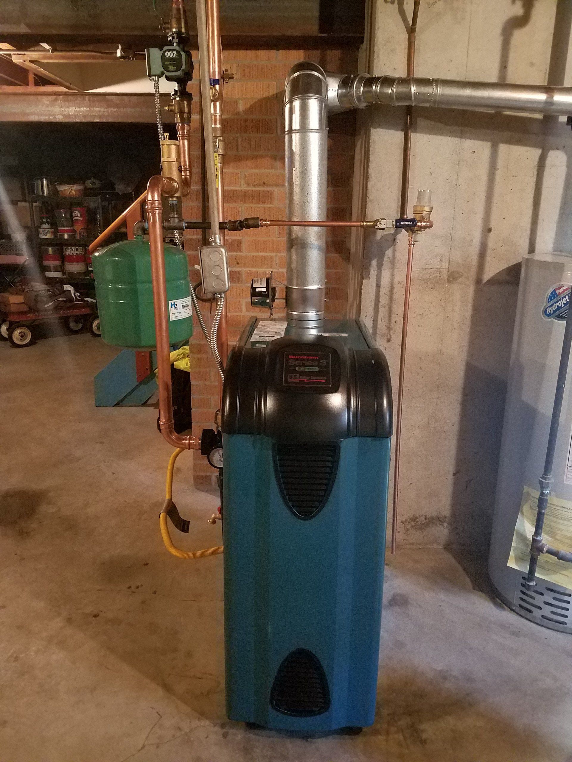 Blue furnace or boiler in a basement with metal vent pipes and a utility setup.