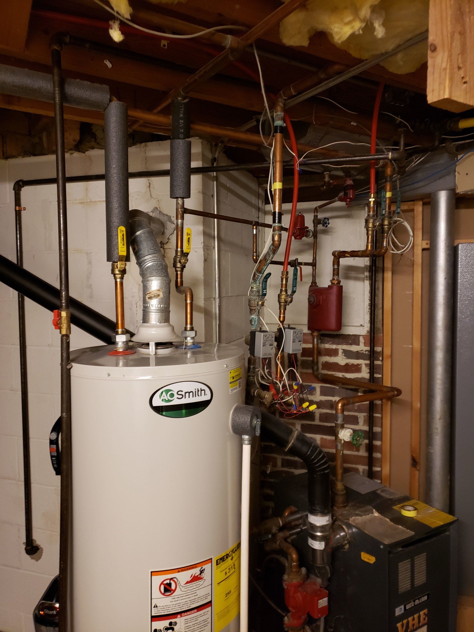Basement utility area with a water heater, exposed pipes, ducts, and HVAC equipment