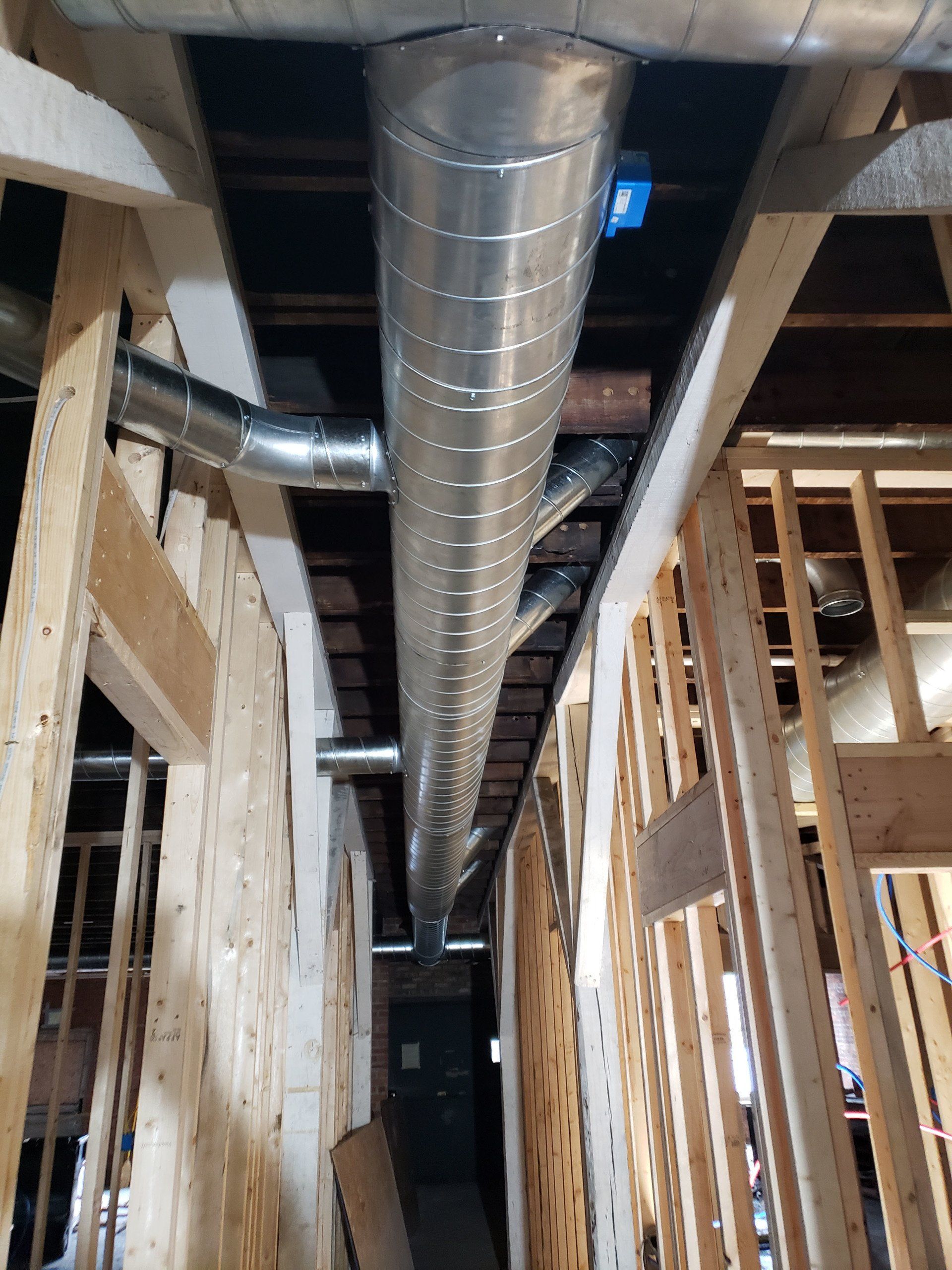 Exposed HVAC duct running through an unfinished framed interior under construction