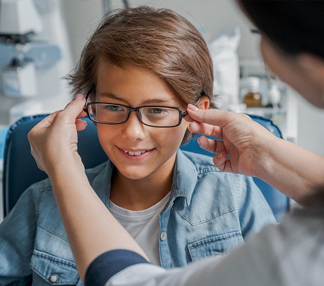 Staff Assisting A Kid With Eyeglass — Defiance, OH — Defiance Vision Care Staff Assisting A Kid With Eyeglass — Defiance, OH — Defiance Vision Care