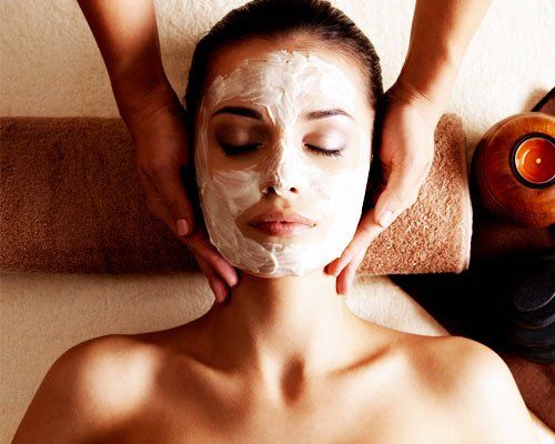 A woman with a facial mask on while getting a massage.