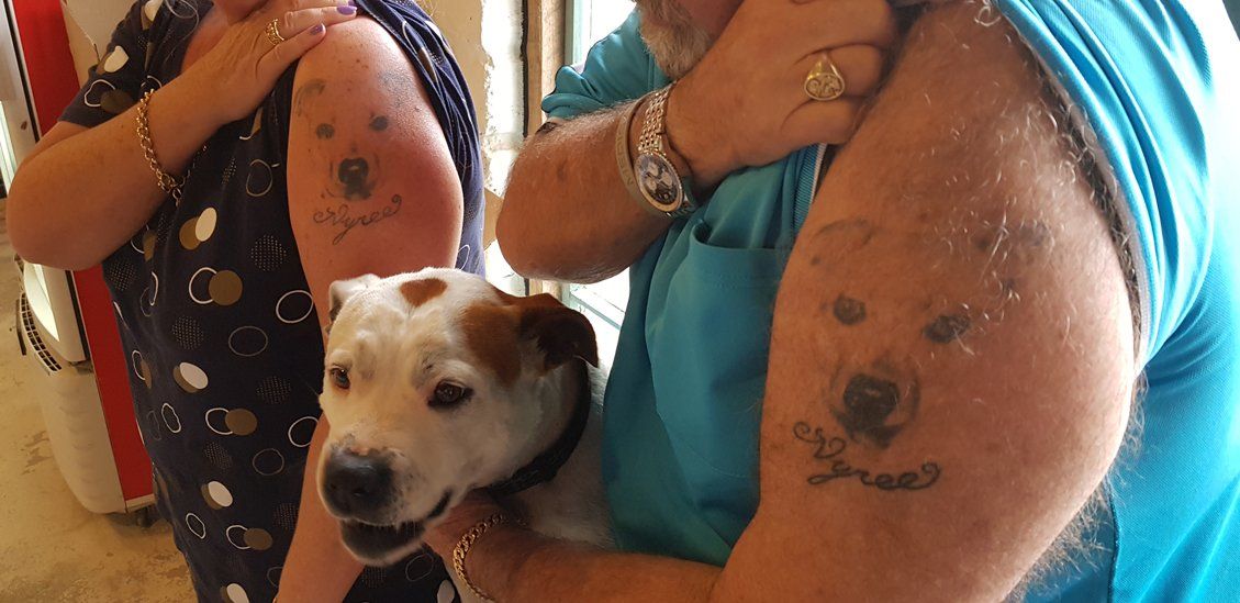 2 guys showing tattoo with dog