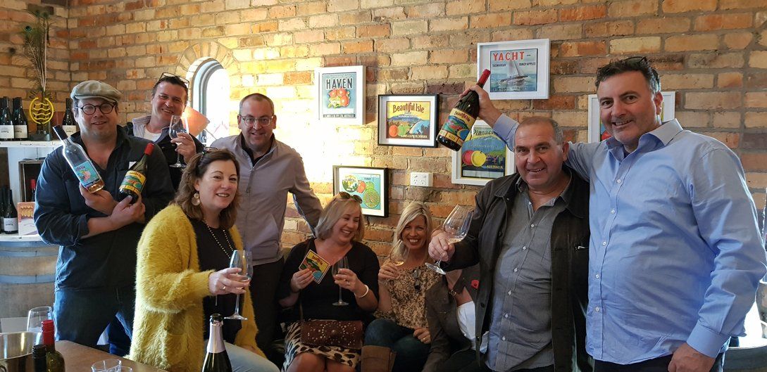 five guys and 3 woman holding wine