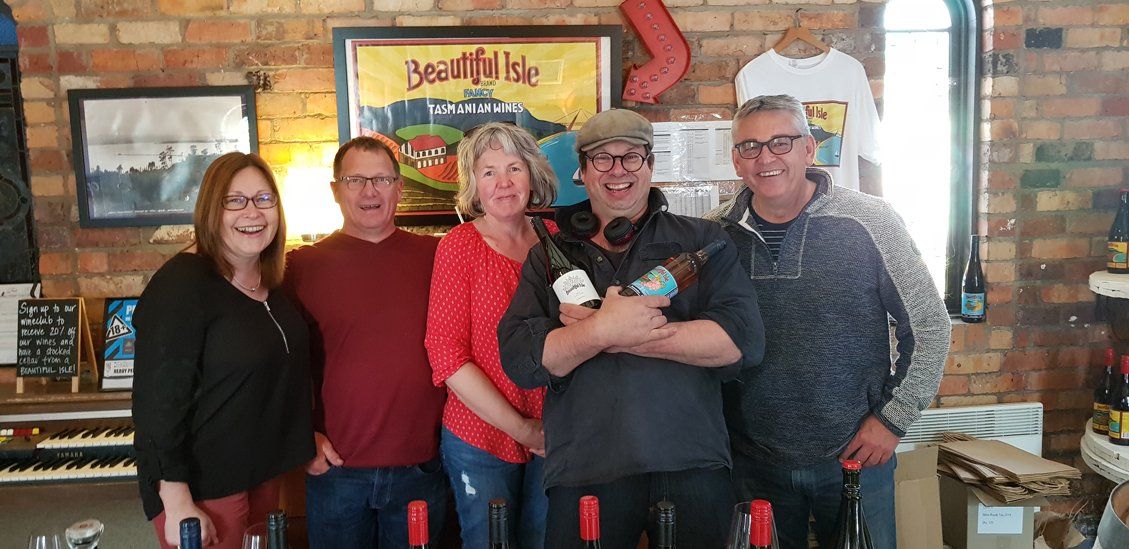 3 guys and 2 woman holding wine