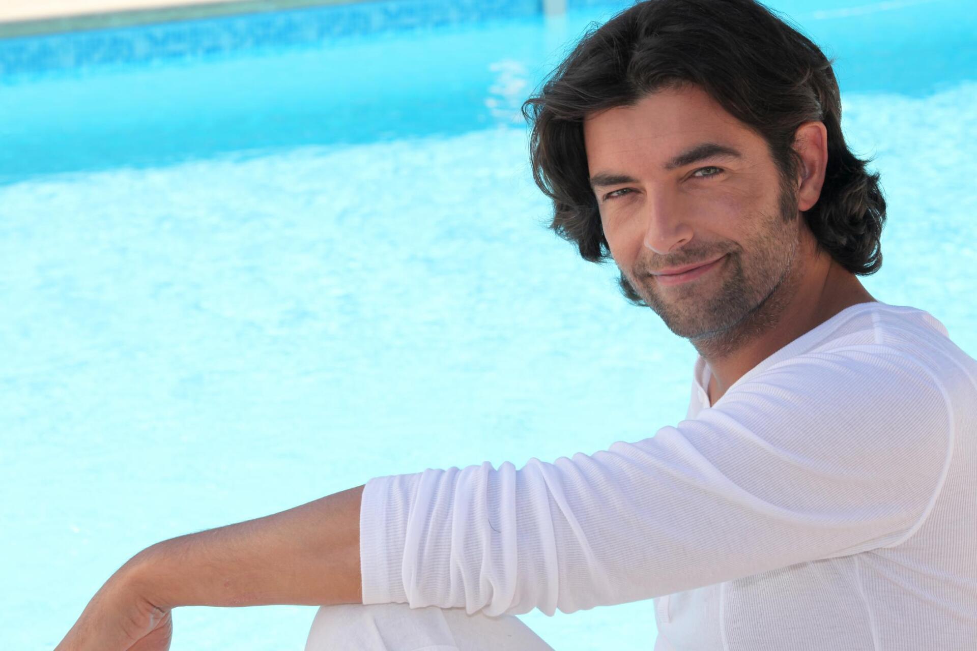 man sitting right next to a swimming pool