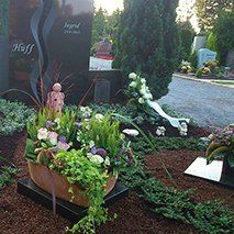 Ein Friedhof mit einem Blumenkasten voller Blumen und Pflanzen.