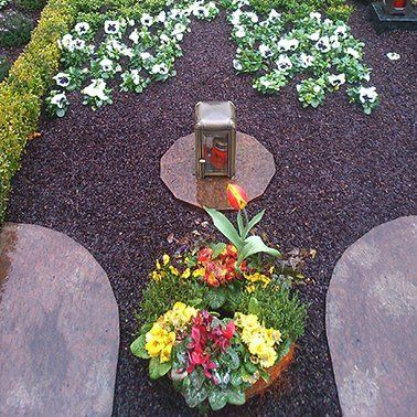 Ein Friedhof mit Blumen und einer Laterne in der Mitte