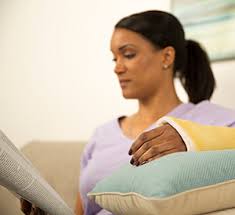 Woman reading while her hand is elevated.