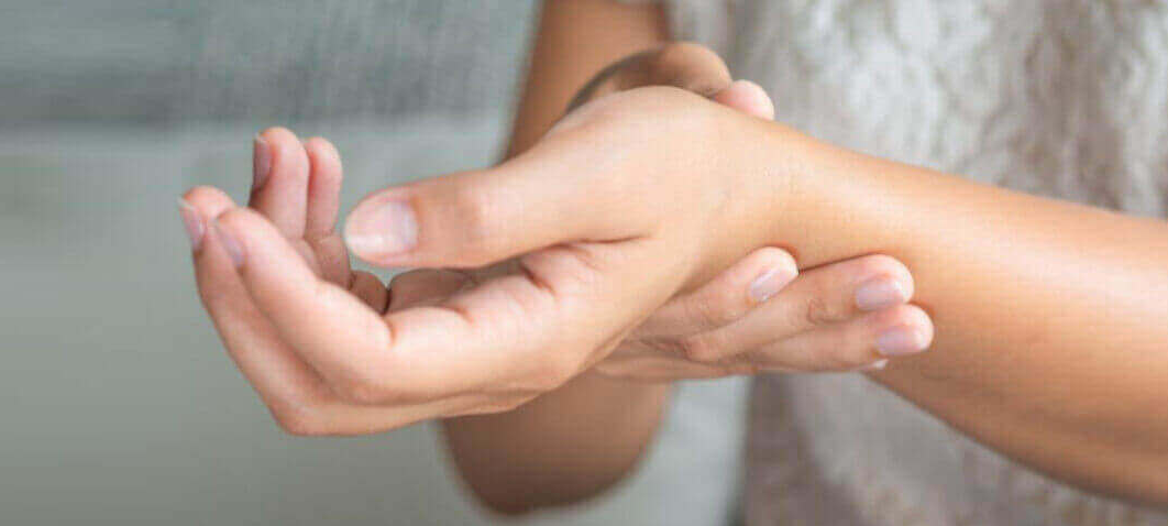 Woman holding her wirst due to pain.