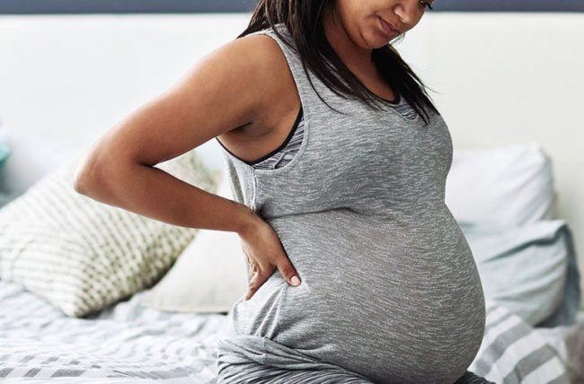 A pregnant brunette awakens with lower back pain.