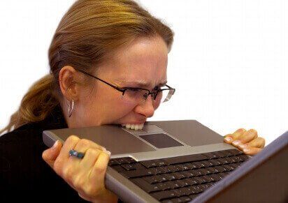 woman biting her laptop due to stress & anxiety