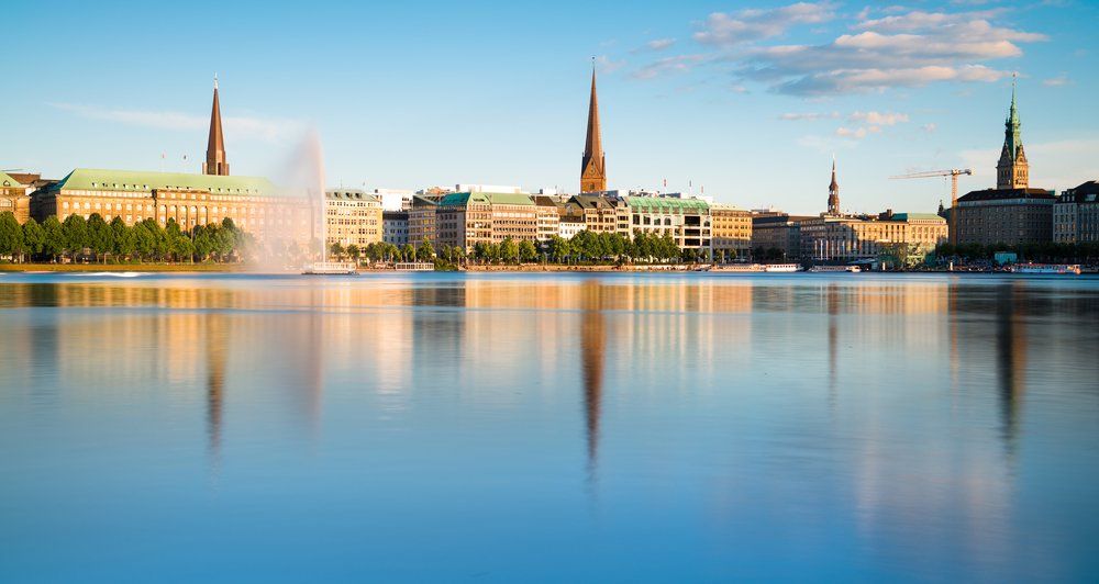 Die Skyline einer Stadt spiegelt sich im Wasser eines Sees.