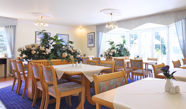 Ein Esszimmer mit Tischen und Stühlen und Blumen auf den Tischen.