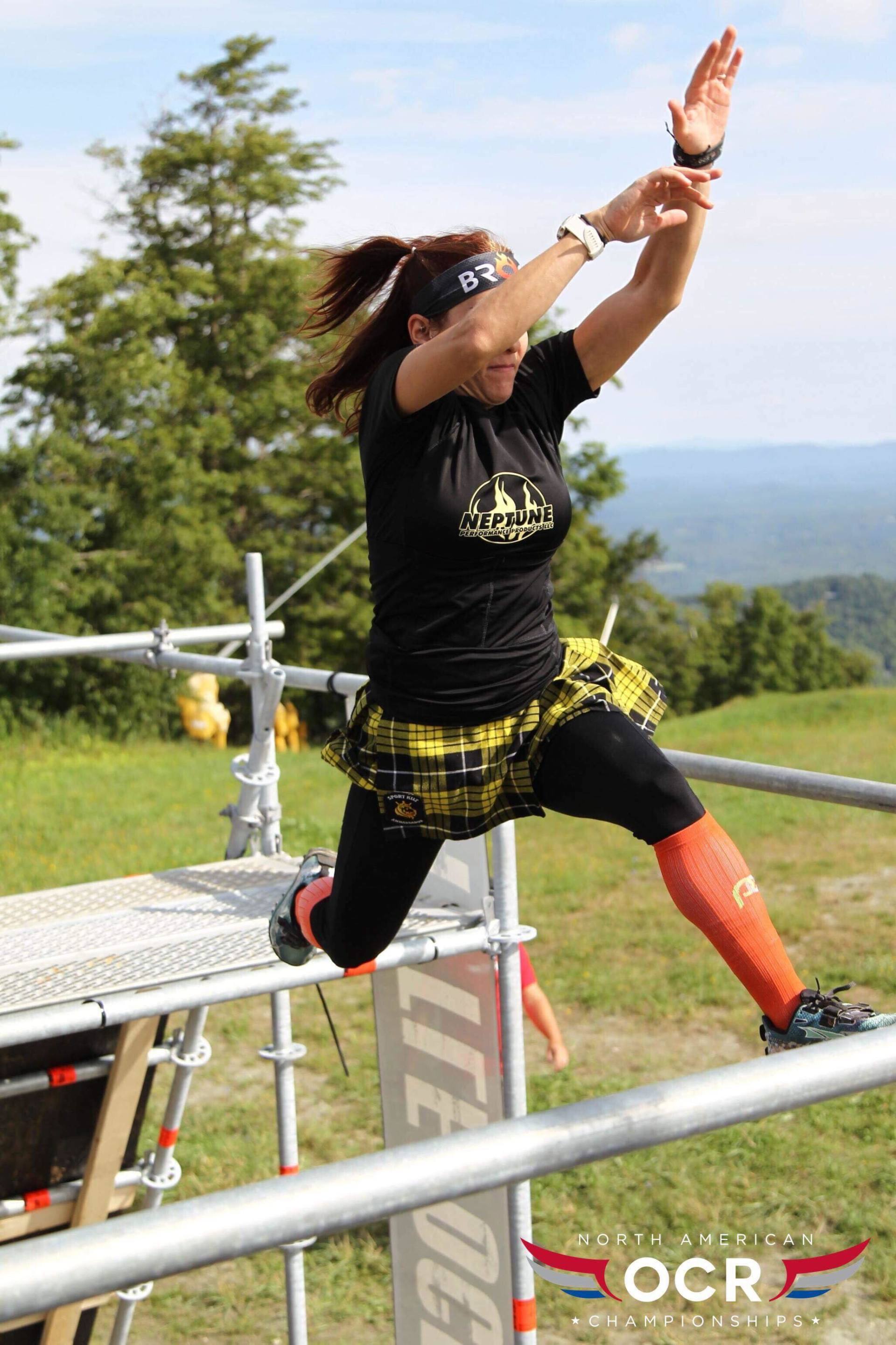 A woman is jumping over a metal fence.
