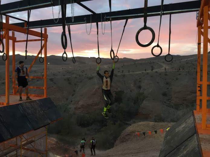 A man is hanging from a bar with rings hanging from it