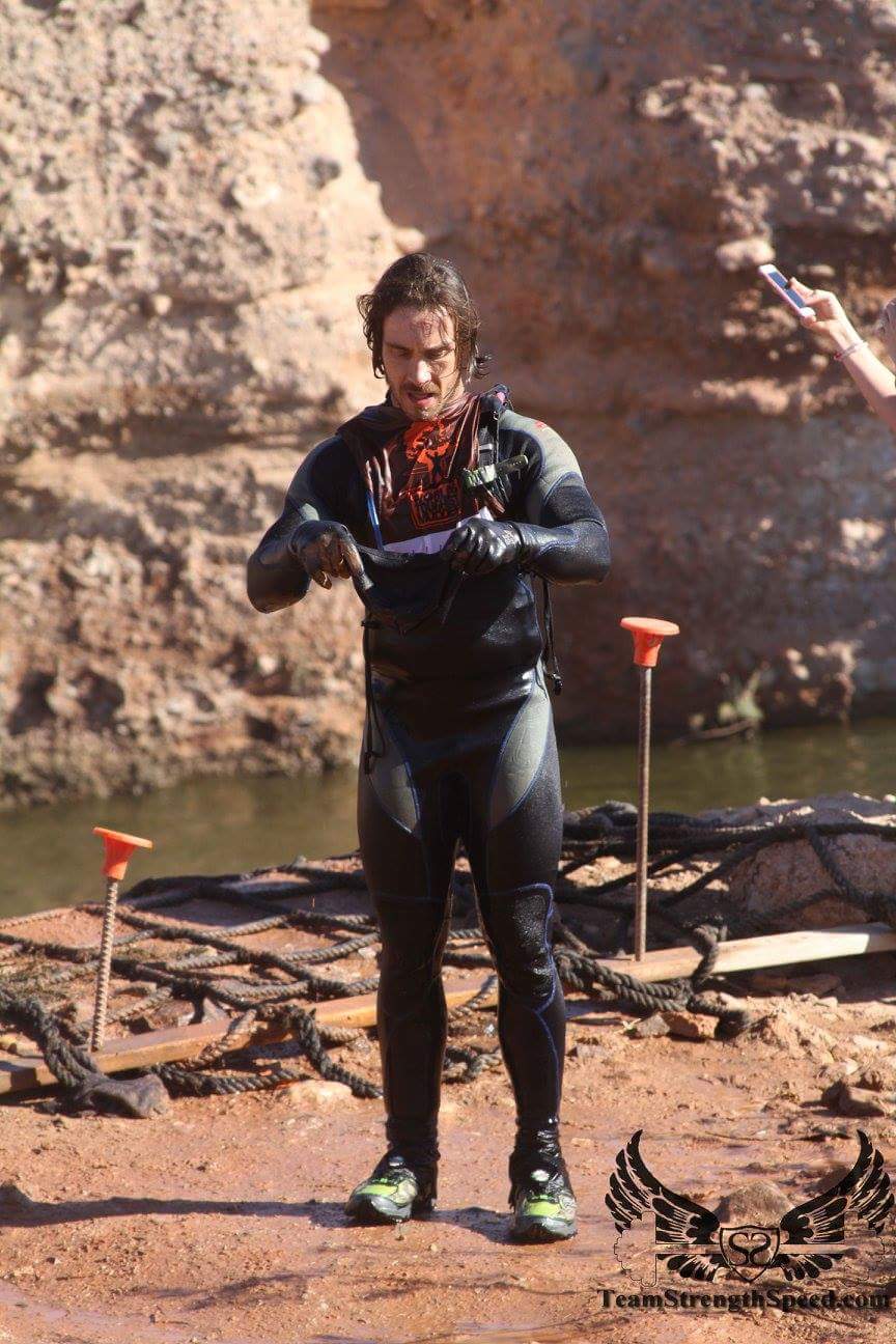 A man in a wetsuit is standing next to a body of water.
