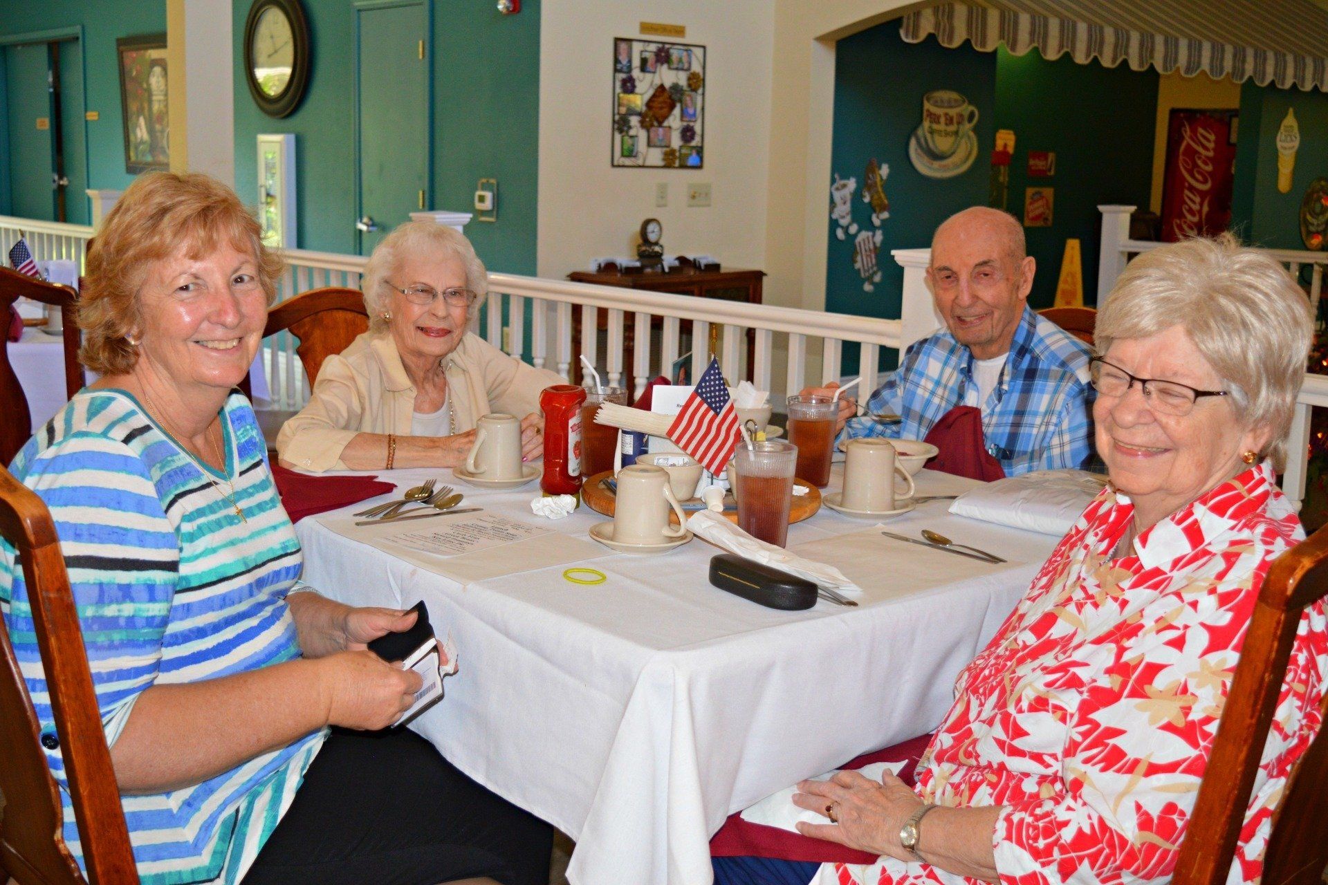Four people seated at a table in a dining room; two women, a man, and a woman smile.