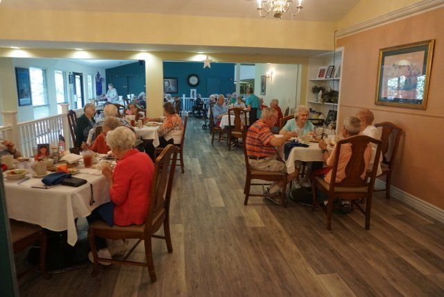 People dining at tables in a brightly lit restaurant with wooden floors.