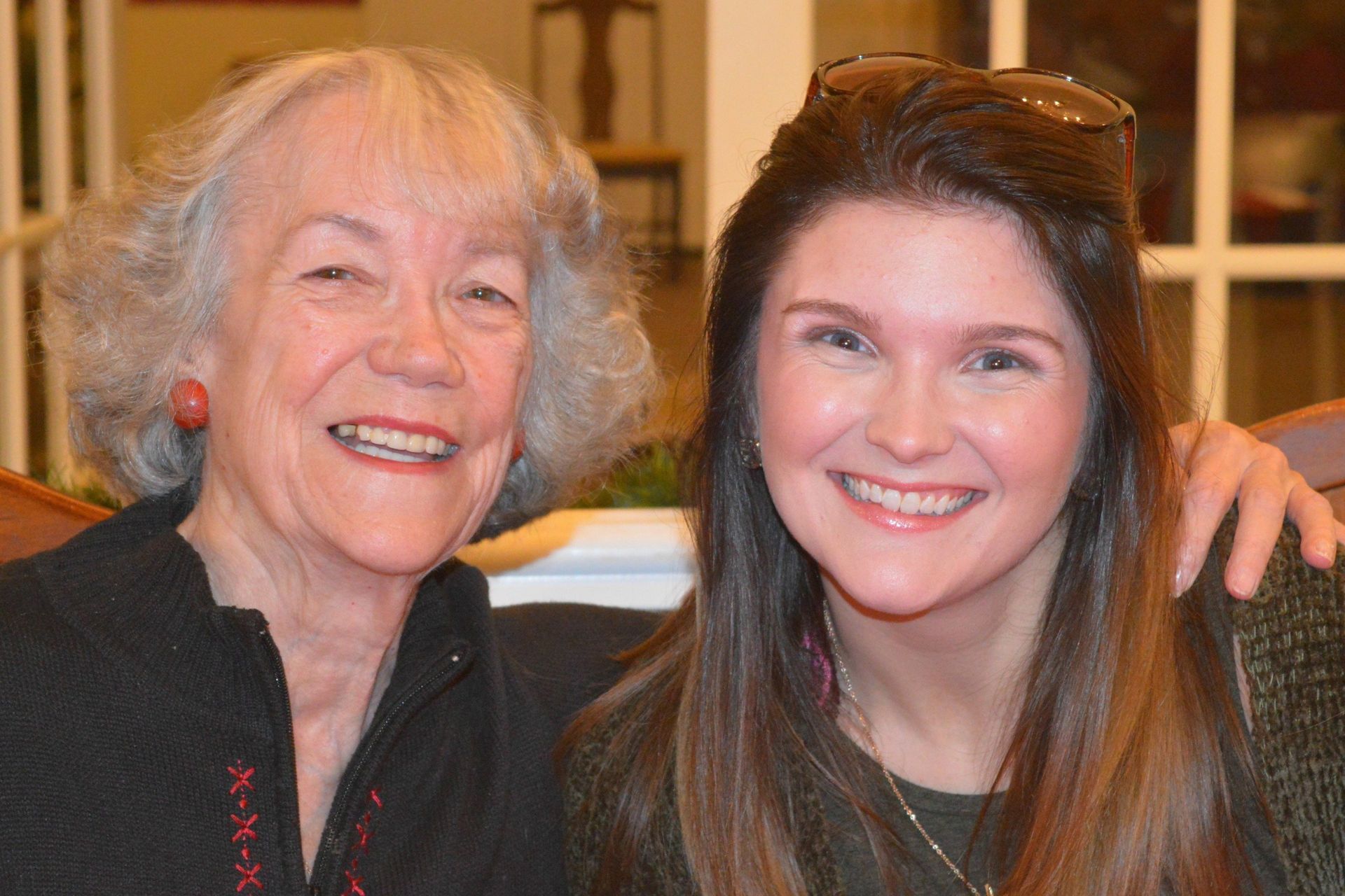 Two smiling women, one older with gray hair, the other younger with long brown hair, pose for a photo.