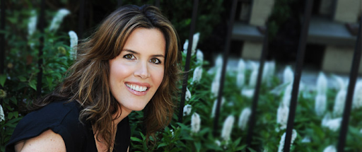 A woman in a black shirt is smiling in front of a fence.