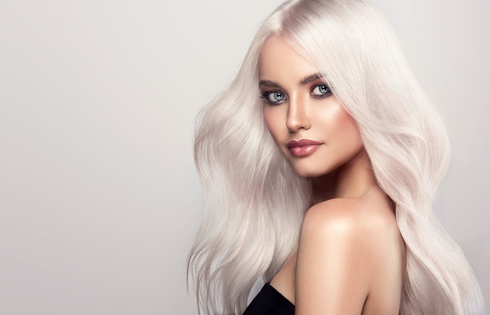 A beautiful woman with long white hair is wearing a black top.