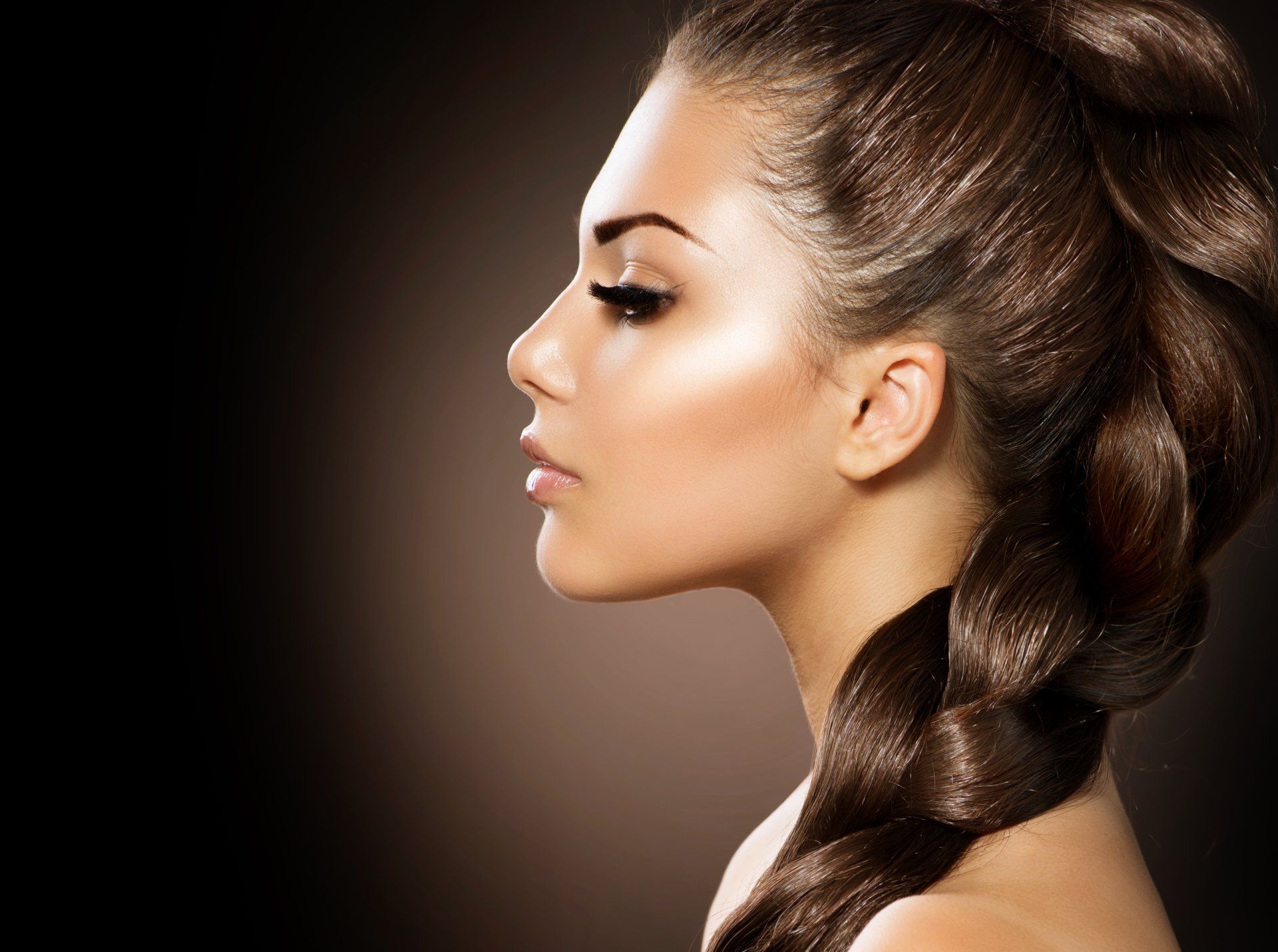 A woman with a braided ponytail is looking at the camera.