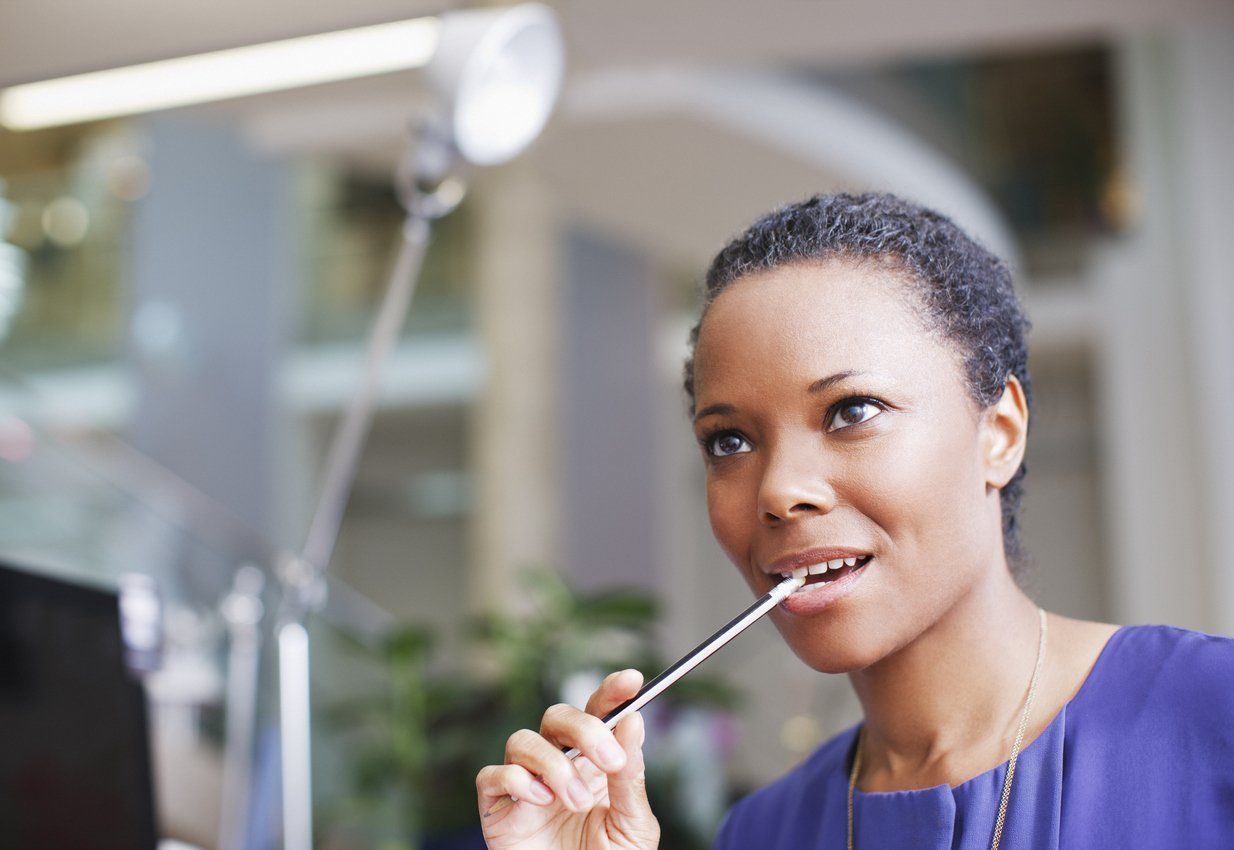woman biting the end of a pencil at work