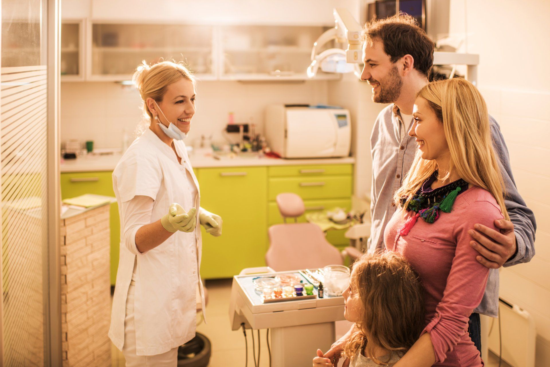 family-with-young-daughter-speaking-to-dentist-in-exam-room