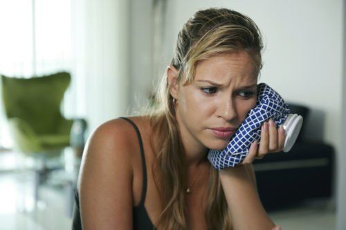 woman holding ice bag over cheek, when do my wisdom teeth need to be pulled blog