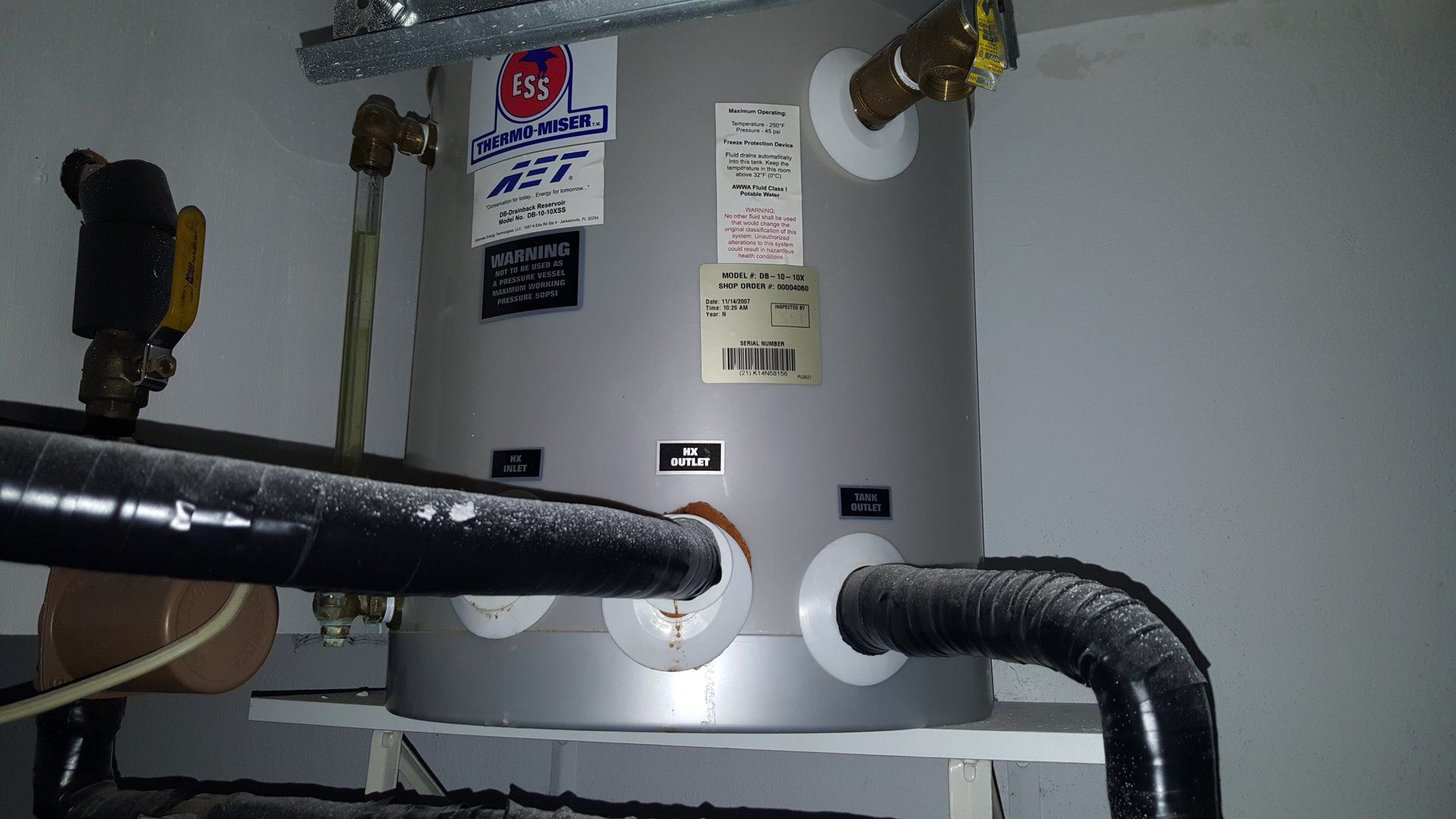 A water heater is sitting on a shelf in a dark room.