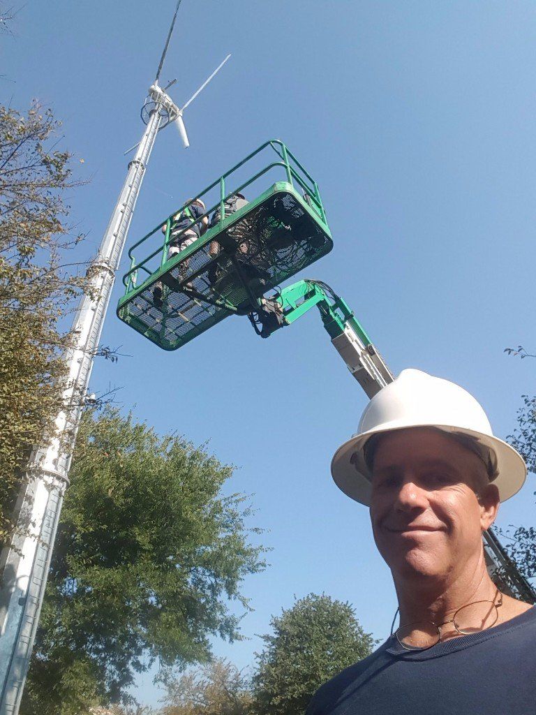 A man wearing a hard hat is standing in front of a crane.