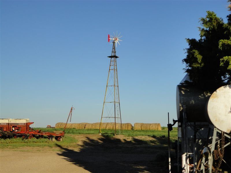 A windmill in a field with hay bales in the background