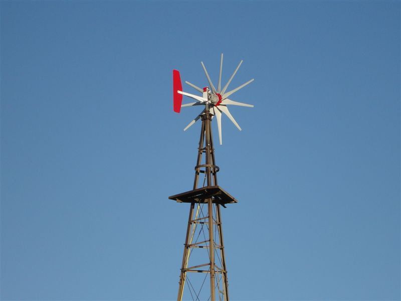 A windmill with a red and white blade against a blue sky