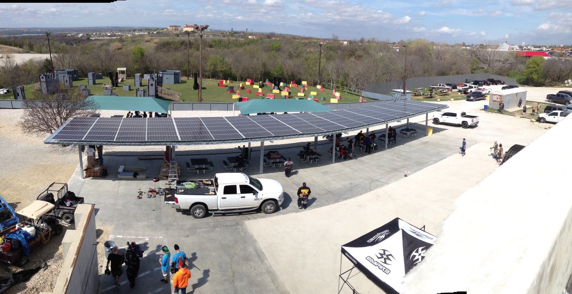 A white truck is parked under a covered area with solar panels.