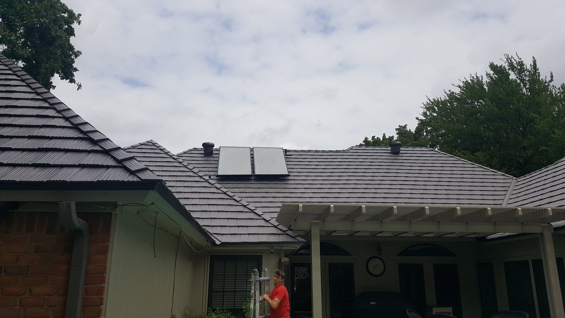 A man is standing in front of a house with a solar panel on the roof.