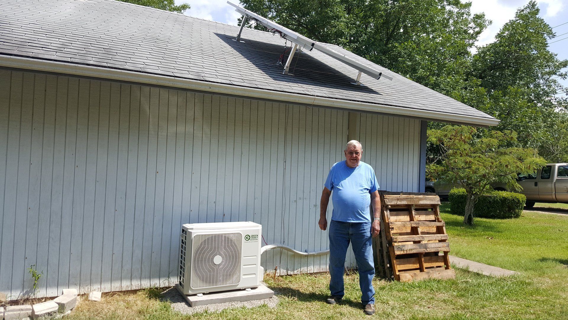A man is standing in front of a house with a broken roof.