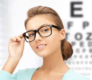 Young woman face in eyeglasses with eye chart — Eye & Contact Lens Clinic in Bremerton, WA Young woman face in eyeglasses with eye chart — Eye & Contact Lens Clinic in Bremerton, WA