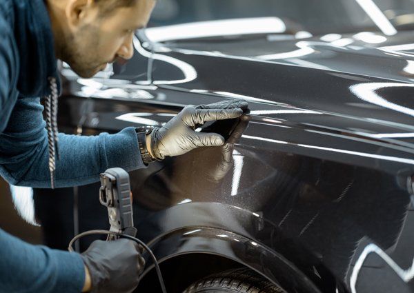 Auto body expert looking closely for a car scratch — Port Allen, LA — Delaune’s Auto Body Auto body expert looking closely for a car scratch — Port Allen, LA — Delaune’s Auto Body