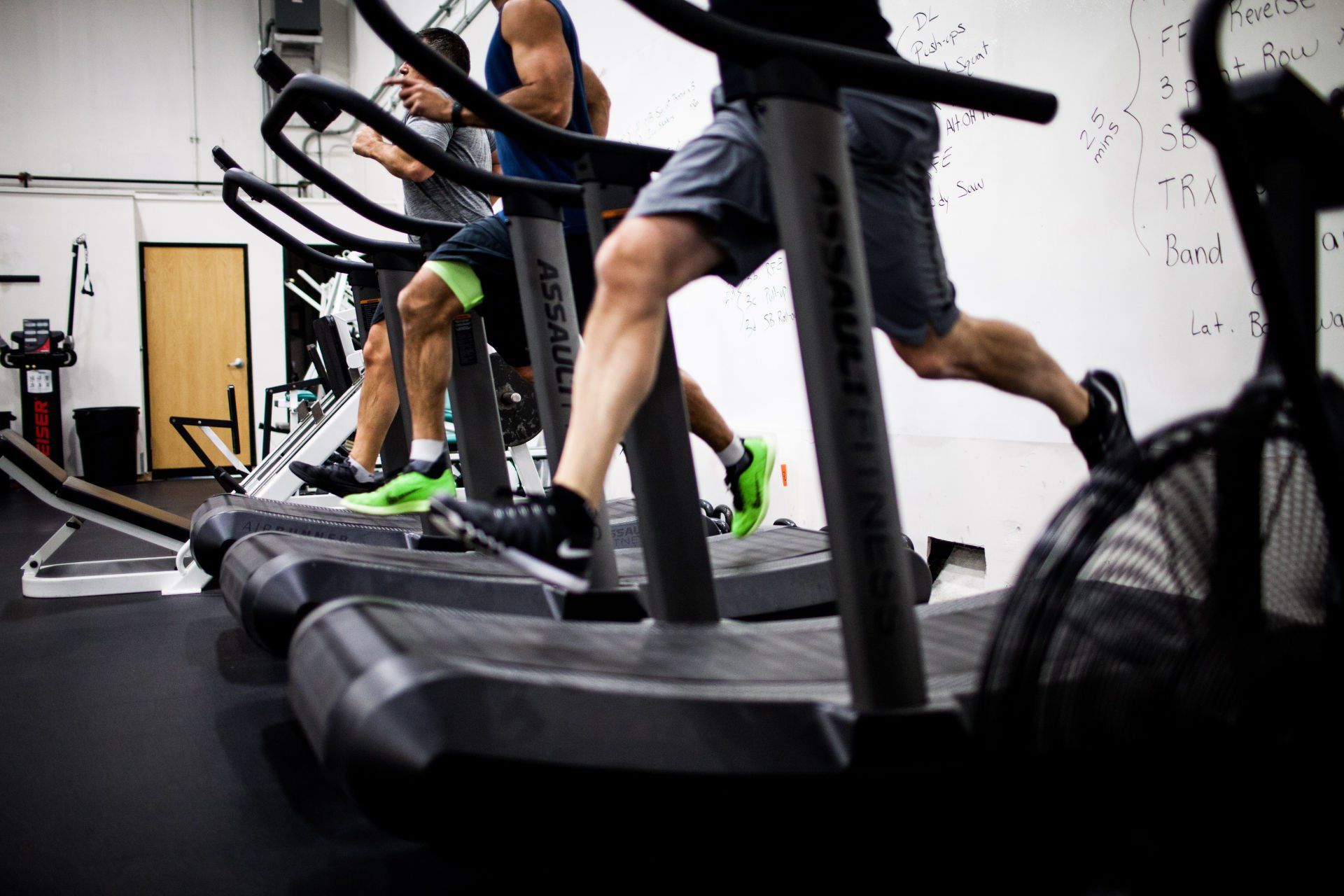 People running on curved treadmills in a gym, legs in motion.