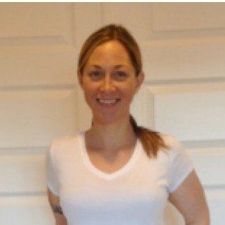 Woman with blonde hair smiles, wearing a white V-neck shirt.