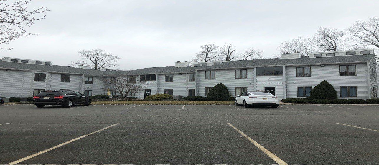 Apartment building on a cloudy day with parked cars in front.