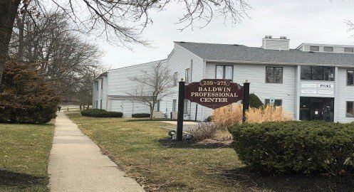 Baldwin Professional Center sign in front of a two-story building. Sidewalk in the foreground.