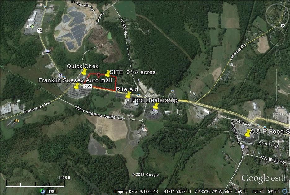 Aerial view map showing roads, buildings, and green landscape; several points marked with yellow pins.