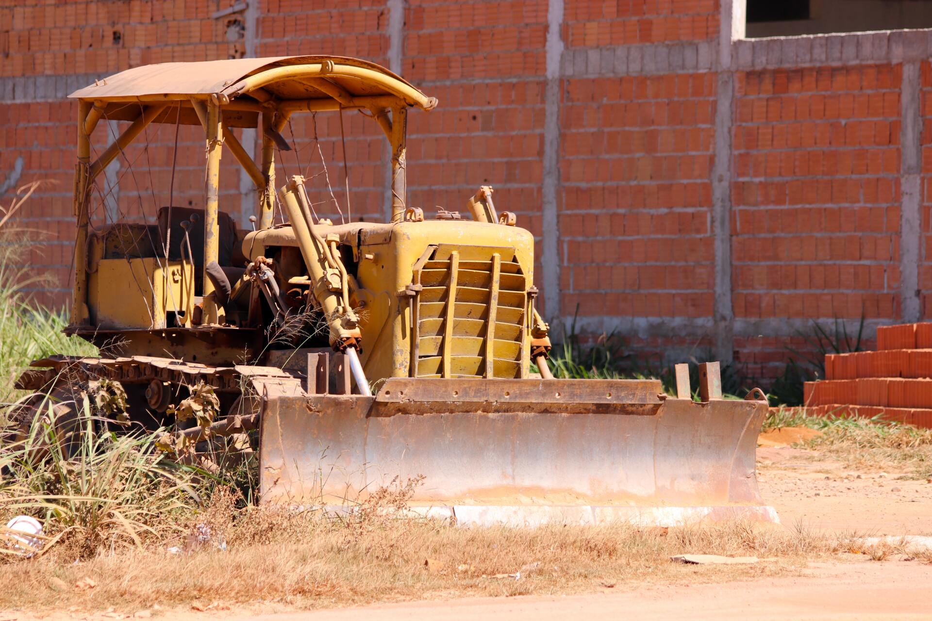 A yellow bulldozer is parked in front of a brick building
