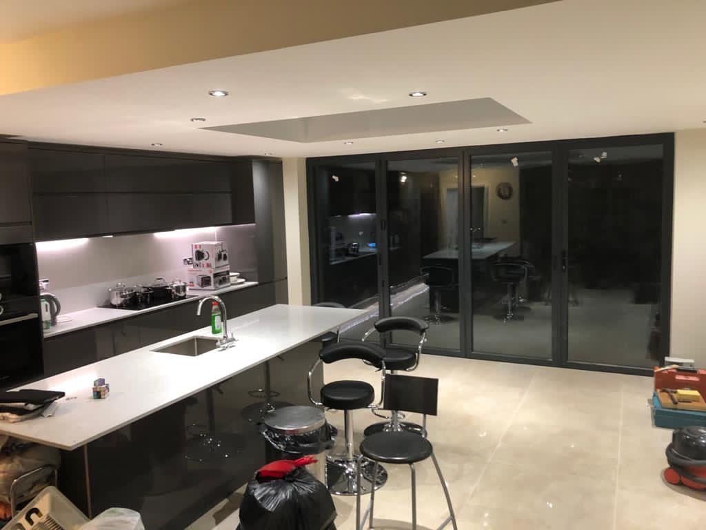 A kitchen with a large island , stools and a sink.